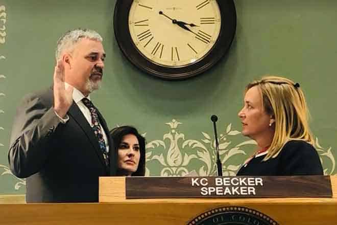 Newly appointed Colorado House District 64 State Representative Richard Holtorf (left) is sworn in to office by Colorado House Speaker KC Becker as his wife, Mary Holtorf, looks on.