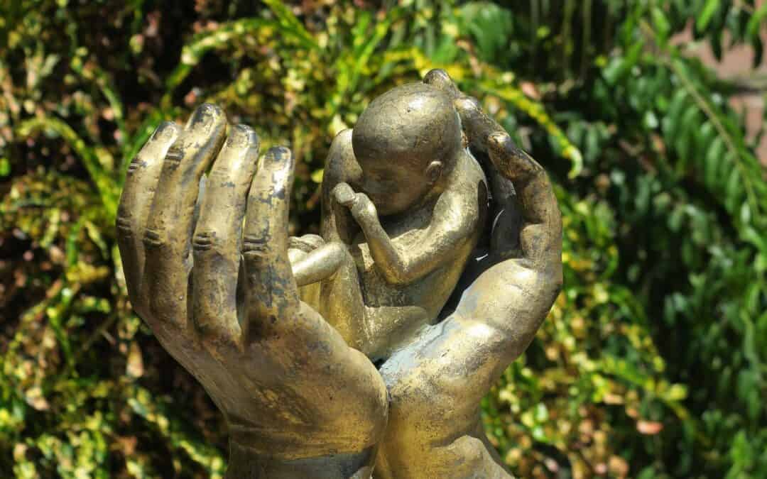 A statue of hands holding a small baby.